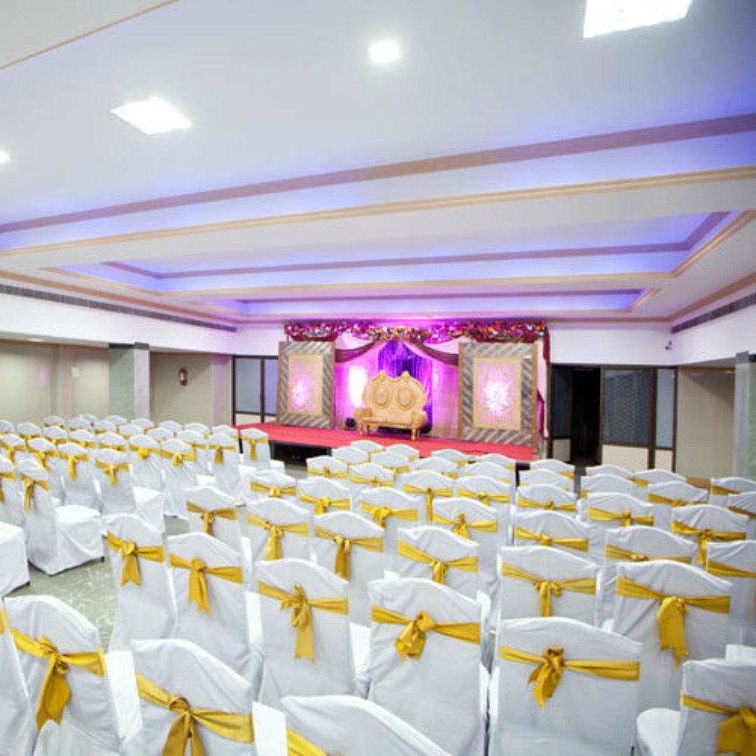 Main hall with white chair covers, gold sashes and the reception stage